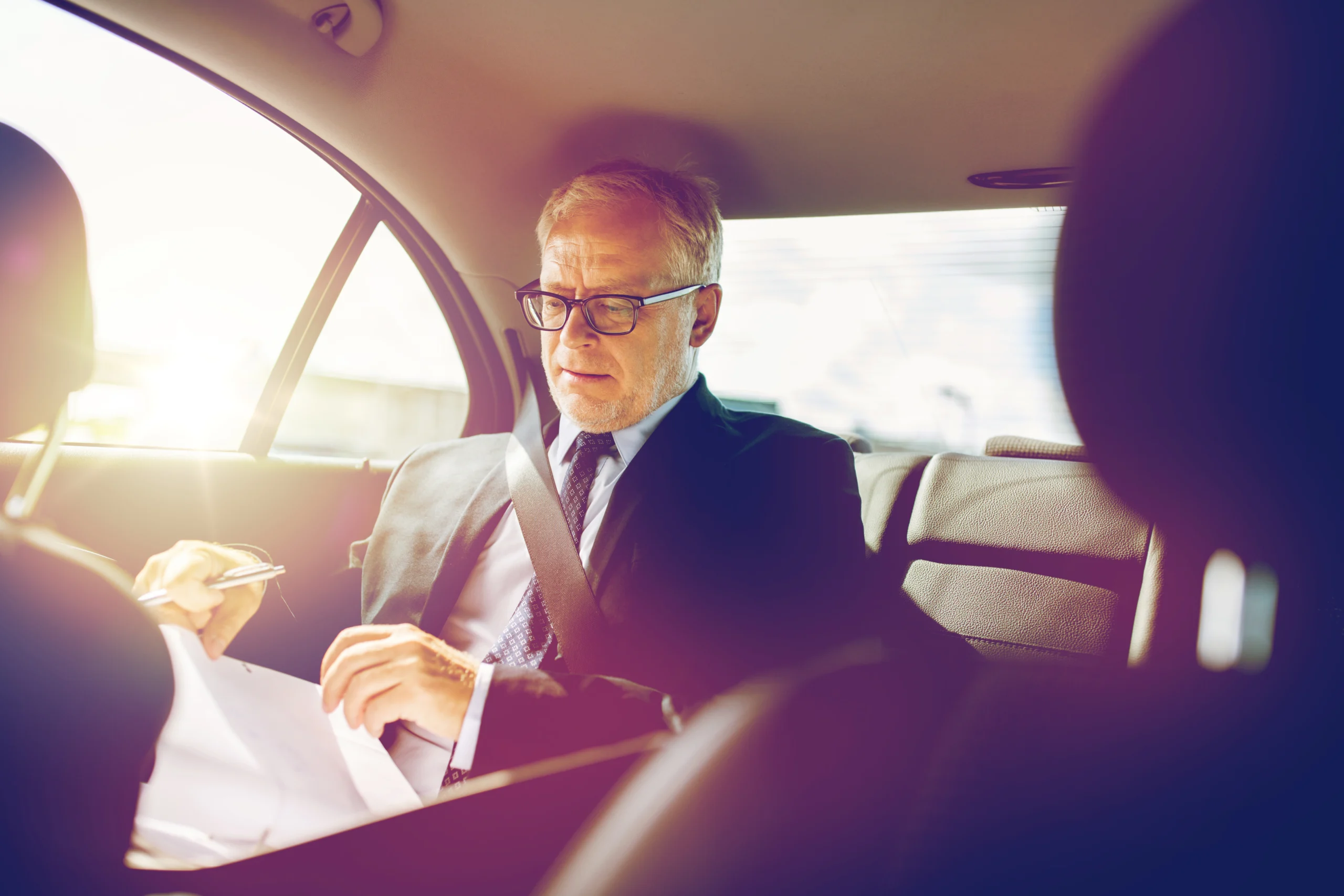senior businessman with papers driving in car